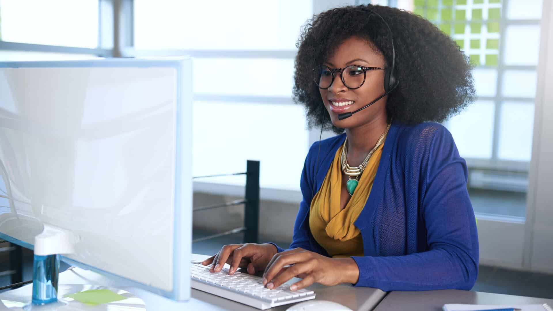 smiling-customer-service-representative-sitting-at-the-computer-smiling-using-a-headset